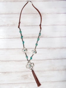 BOOTS, JEANS, TURQUOISE SILVER CROSS CONCHO WITH BROWN LEATHER TASSEL ON A NAVAJO PEARL NECKLACE